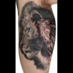 Black and grey lion with blue eyes tattoo portrait